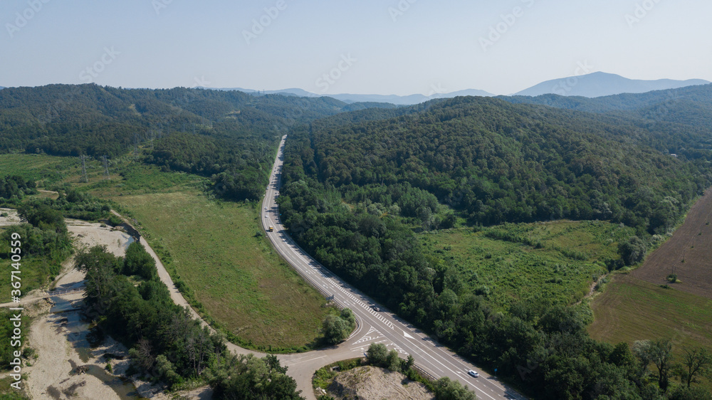 Aerial view from above of curve highway road with a car with green forest in Russia