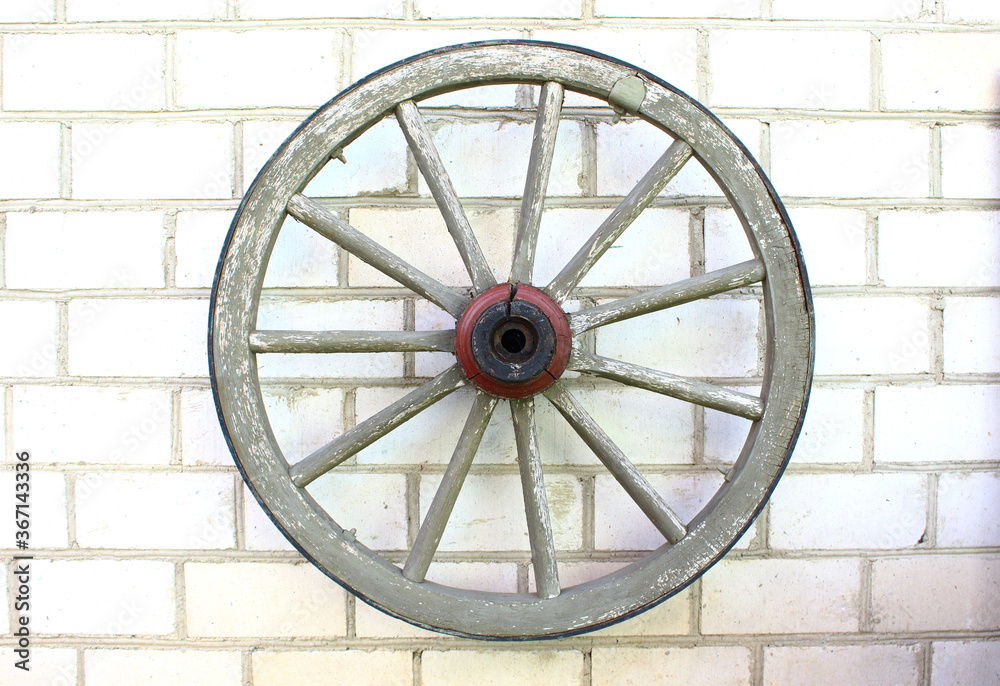 old wooden wheel hanging on a brick wall.