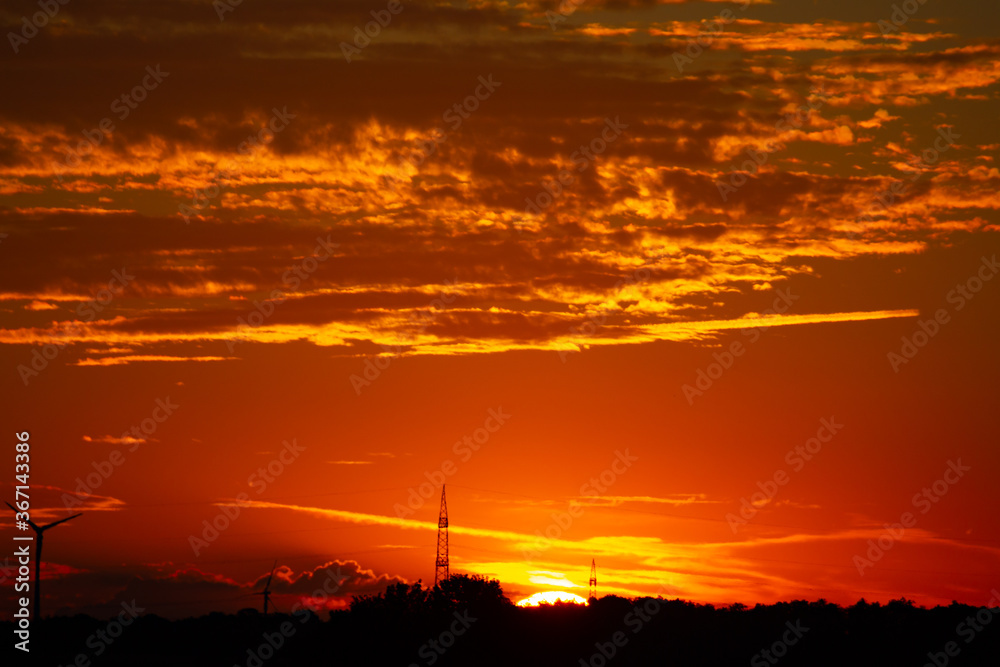 Sunrise with silhouettes of wind turbines on the horizon
