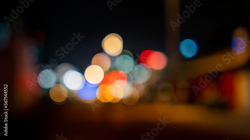 Defocused lights in the middle of a dark, empty street at night