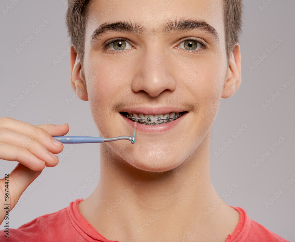 Teen boy cleaning braces. Young man taking care of his teeth. Dental hygiene. Teenager brushes braces. Teen boy cleaning braces. Young man taking care of his teeth. Dental hygiene. Teenager brushes braces.