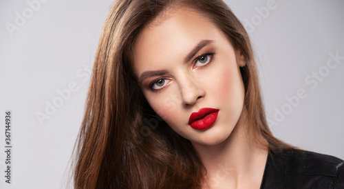 Portrait of beautiful young woman with bright makeup. Beautiful brunette with bright red lipstick on her lips. Pretty girl with long brown hair. Brunette dressed in a black. Sexy girl