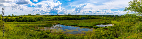 A beautiful panoramic view of a pond hidden at the bottom of a lush valley near Saskatoon Saskatchewan, Canada  © Sask Photography