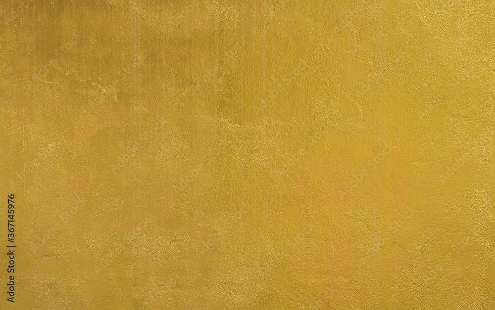 Gold wall texture background. Yellow shiny gold foil paint on wall surface with light reflection