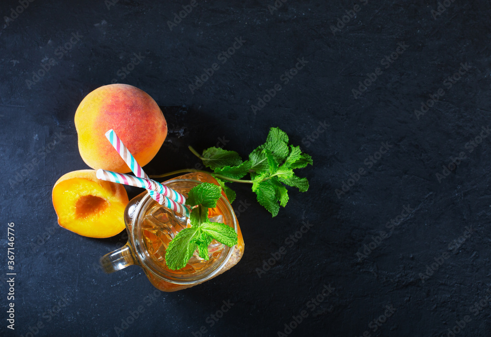 Peach ice tea drink on dark background with mint and ice