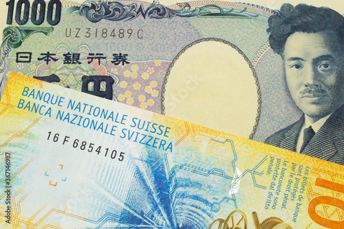 A macro image of a Japanese thousand yen note paired up with a yellow Swiss ten franc bill. Shot close up in macro.