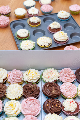 Home baked cupcakes beautifully decorated with buttercream on top neatly placed in carton transport container.
