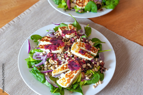 Fresh and healthy vegetable salad with chunks of grilled halloumi goat cheese and a dollop of delicious blueberry sauce on top.