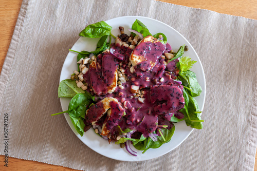 Fresh and healthy vegetable salad with chunks of grilled halloumi goat cheese and a dollop of delicious blueberry sauce on top.