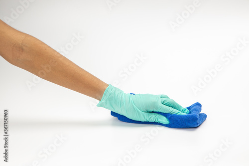 Close up of hands in rubber protective green gloves cleaning the blue surface with a rag. Home, housekeeping concept