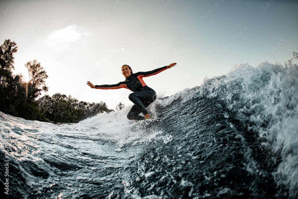 Active young wet woman in wetsuit balanced on surfboard and rides on the wave. Active young wet woman in wetsuit balanced on surfboard and rides on the wave.
