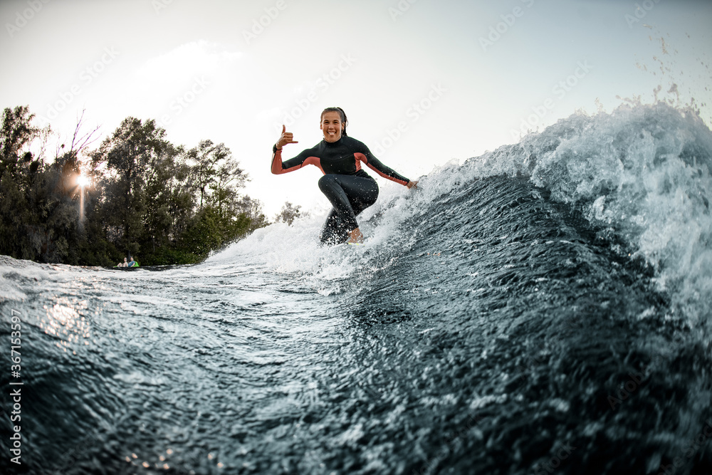 woman in wetsuit balanced on surfboard and rides on the wave.