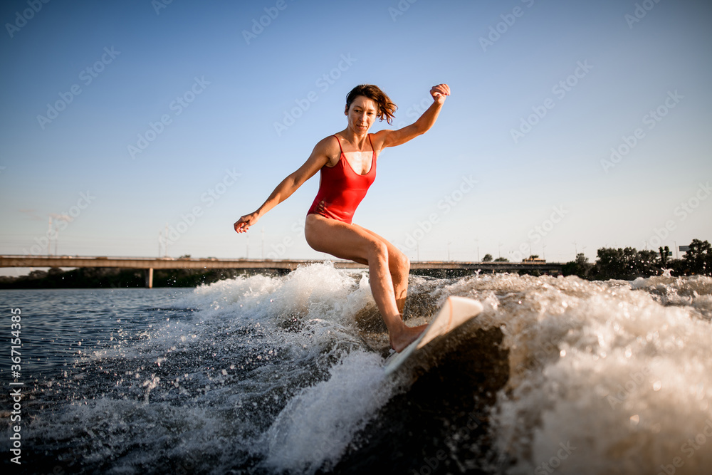 athletic woman masterfully rides the wave on surfboard