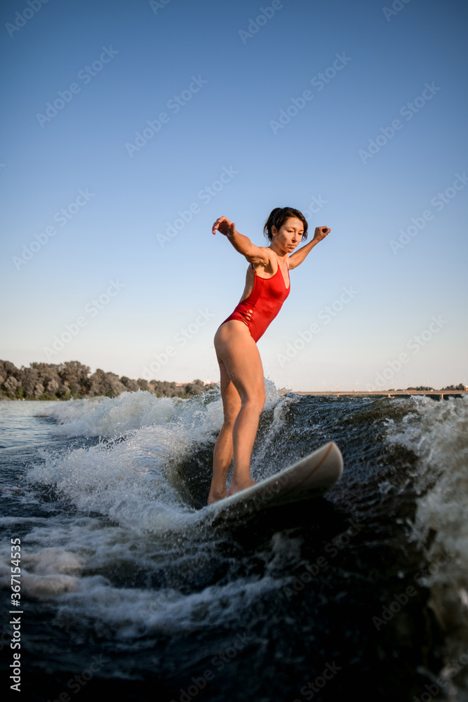 woman in red swimsuit balanced on surfboard and rides on the wave. woman in red swimsuit balanced on surfboard and rides on the wave.
