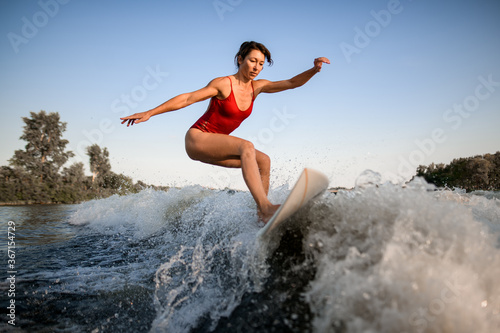 view on athletic woman who masterfully rides the wave on surfboard