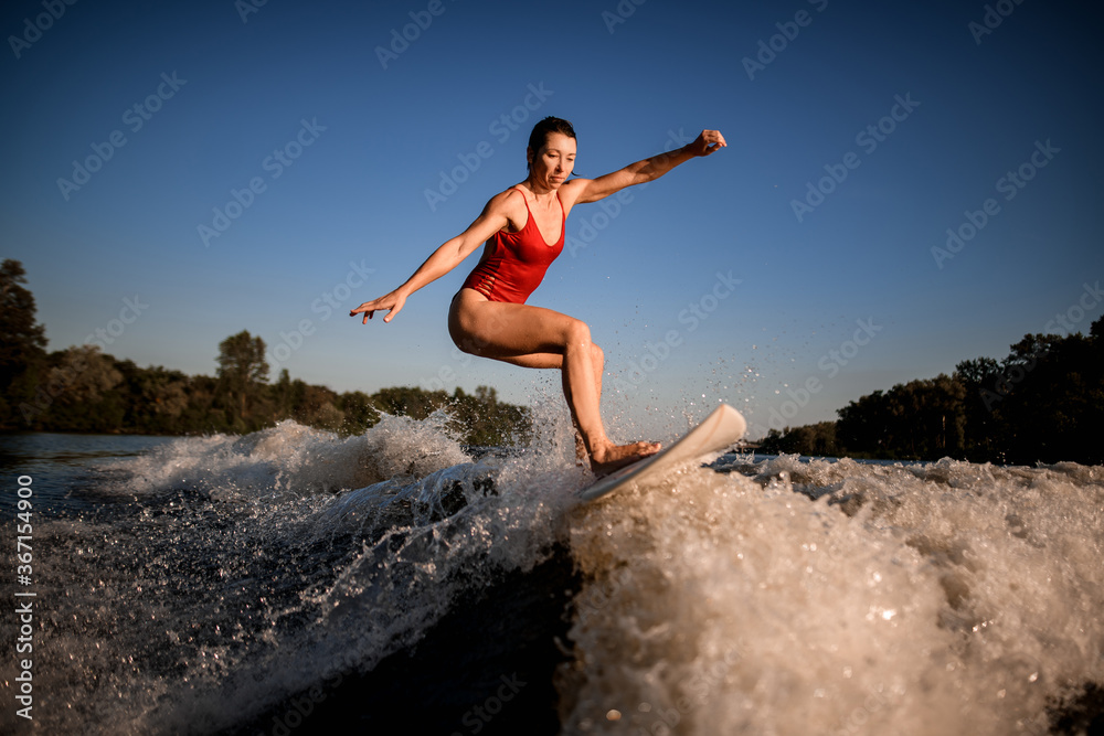Active sports woman masterfully rides the wave on surfboard