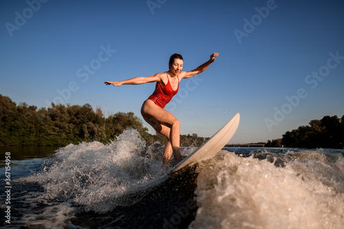 sports woman masterfully rides the wave on surfboard