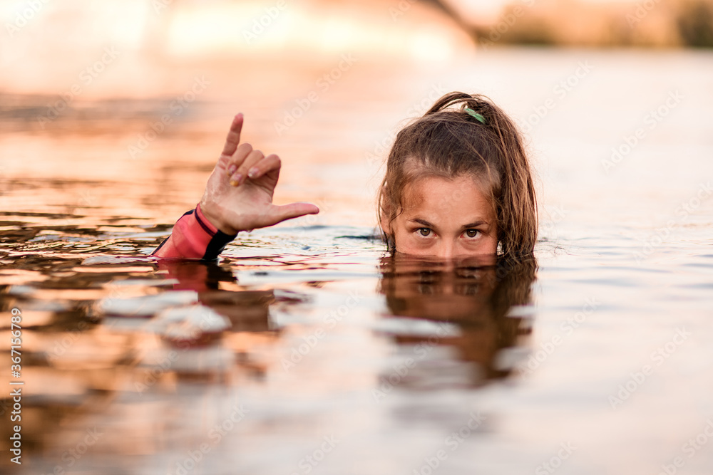 Φωτογραφία head of young woman half emerges from the water and her hand shows gesture of gr