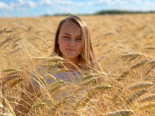 beautiful woman walks in a field with ears, takes pictures in a wheat field

