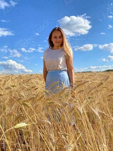 beautiful woman walks in a field with ears, takes pictures in a wheat field
