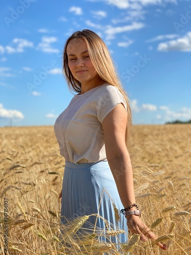 beautiful woman walks in a field with ears, takes pictures in a wheat field
