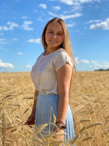 beautiful woman walks in a field with ears, takes pictures in a wheat field
