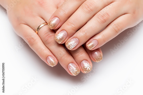 Winter manicure with painted snowflakes. Golden shiny manicure on square short nails close-up on a white background
