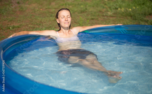 Beautiful woman splashing in inflatable swimming pool outdoor  having fun