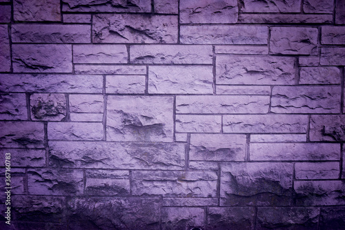 Purple tinted brick wall with grunge effect, vignette and natural texture.