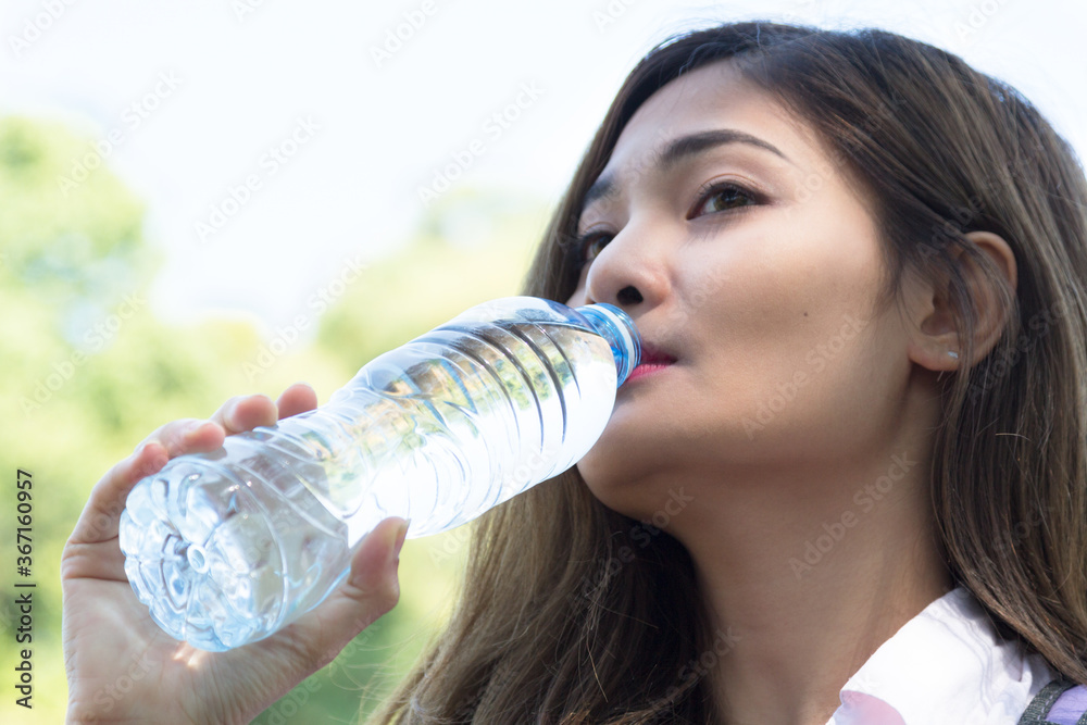 Young beautiful woman traveler drinking water in the forest. Summer traveling concept. Young beautiful woman traveler drinking water in the forest. Summer traveling concept.