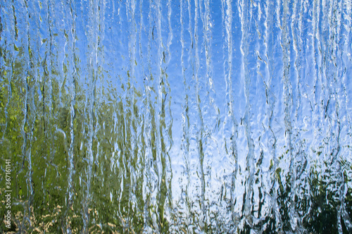 The texture of a transparent water wall from jets of water flows down. Close-up view