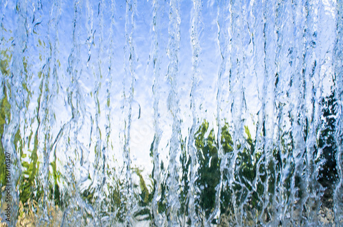 The texture of a transparent water wall from jets of water flows down. Close-up view