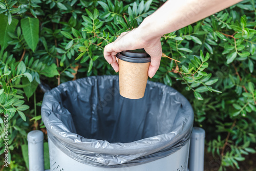 hand of a caucasian woman trashing a cup of take away coffee in a bin photo