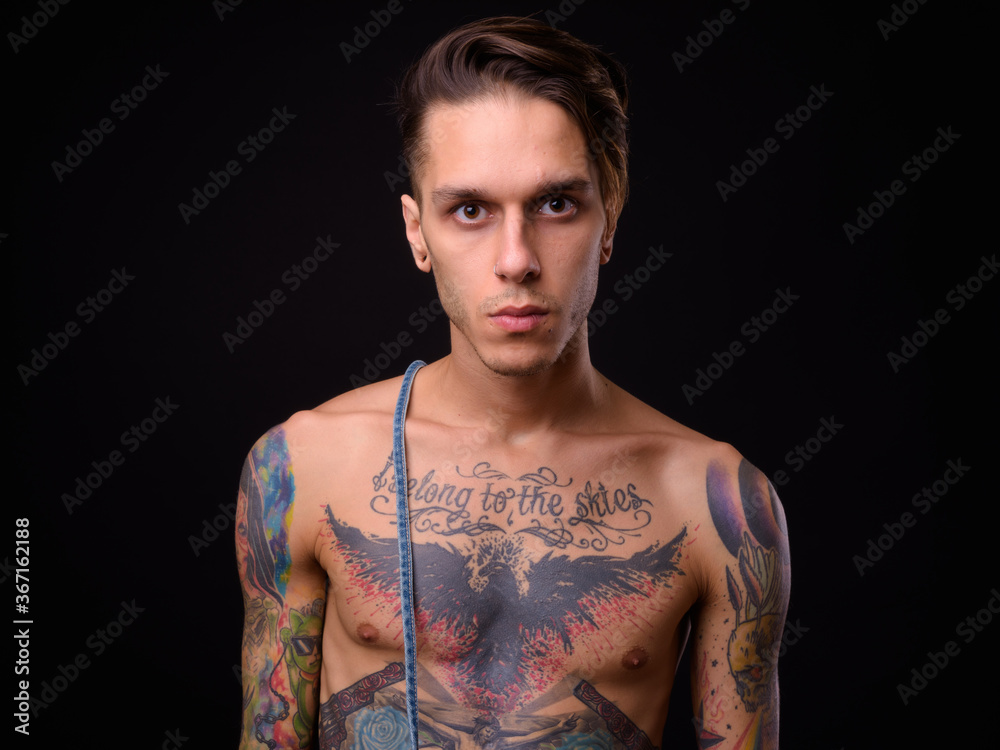 Naklejka premium Young handsome rebellious man shirtless against black background