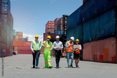 Team of effectively managing staff workers walking together at logistic shipping cargo containers yard
