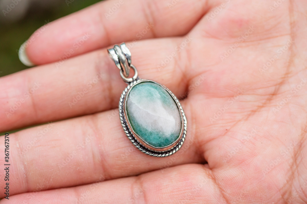 Outdoor close up of hand showing agate mineral gemstone oval pendant Outdoor close up of hand showing agate mineral gemstone oval pendant
