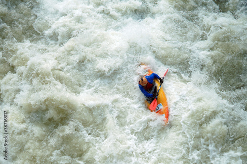 A man on a kayak goes down a stormy mountain river