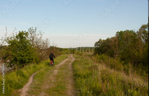 man riding bicicle on green grass near trees © bicdibus