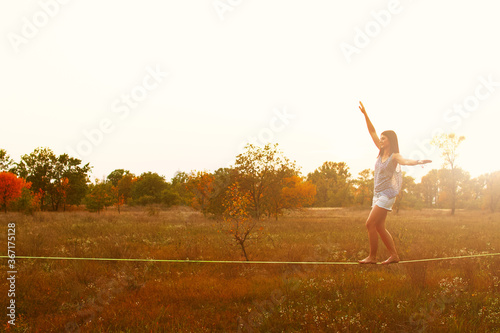Mid Caucasian woman practicing slackline at sunset in the forest. photo