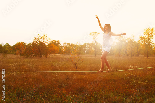 Mid Caucasian woman practicing slackline at sunset in the forest.