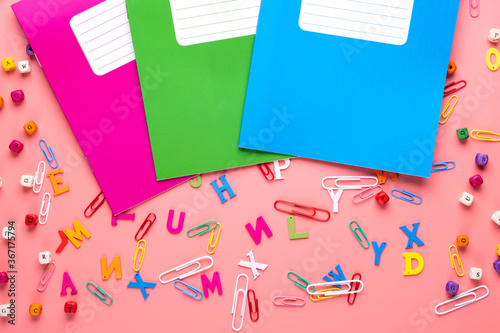 Colorful school exercise books on pink background.