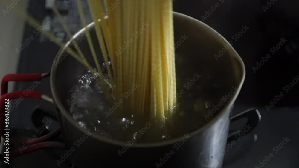 一人用の小さな小鍋で沸騰したお湯にラーメンを投入して茹でるスローモーション