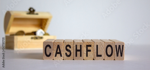 Concept word 'cashflow' on cubes on a beautiful white background, small chest with coins. Business concept.