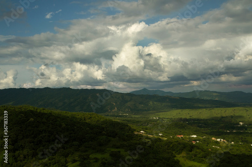Countryside landscape. Aerial view of the village in the green valley at the foot of the hills, under a dramatic sky,  © Gonzalo