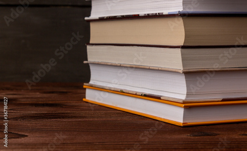 Close-up stack of books on a wooden table with space for text. Books in the library on the table. Literature about business. Novels and tales, adventures, stories. The background for design.