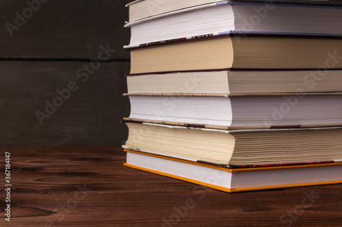 Close-up stack of books on a wooden table with space for text. Books in the library on the table. Literature about business. Novels and tales  adventures  stories. The background for design.
