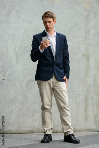 Full body shot of young handsome businessman in suit outdoors