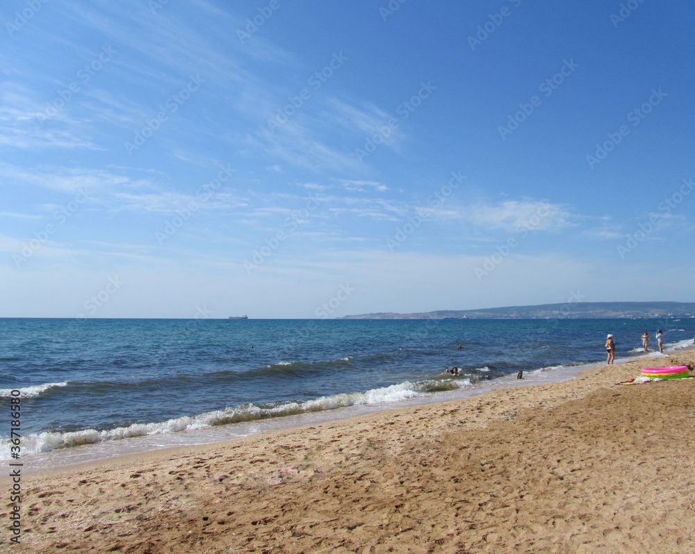 Crimea. Feodosia. Wild beach near the city. Sea, blue sky, yellow sand