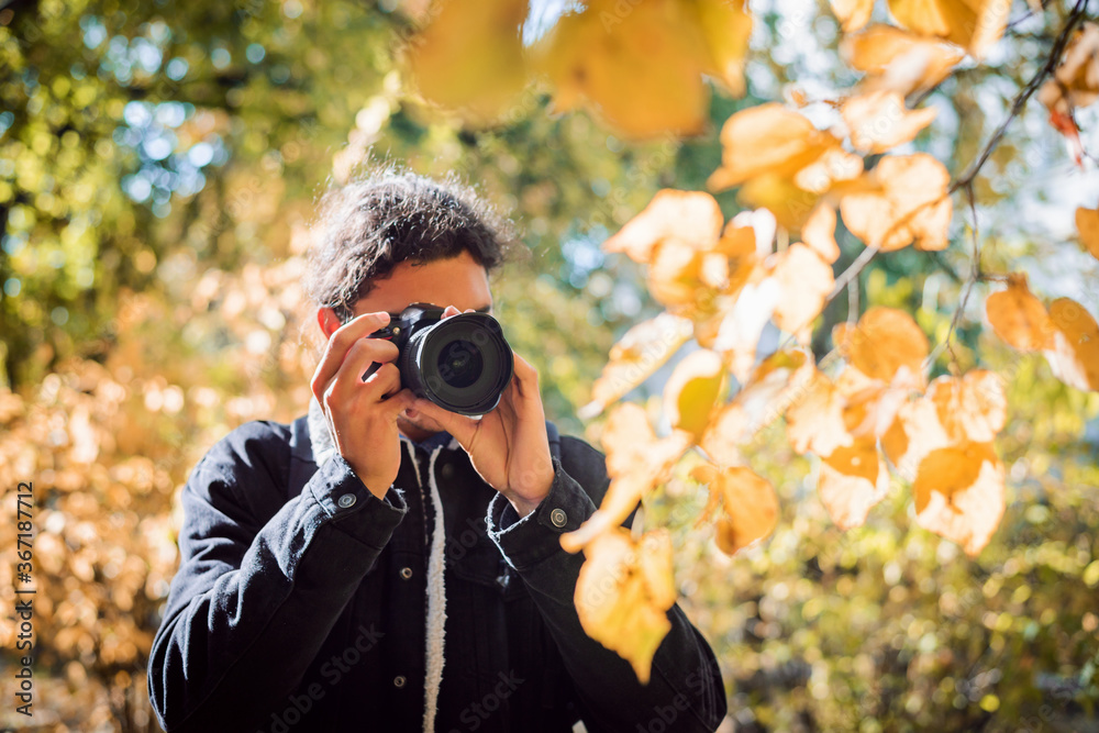 Male amateur photographer shooting autumn leaves in the city park Male amateur photographer shooting autumn leaves in the city park