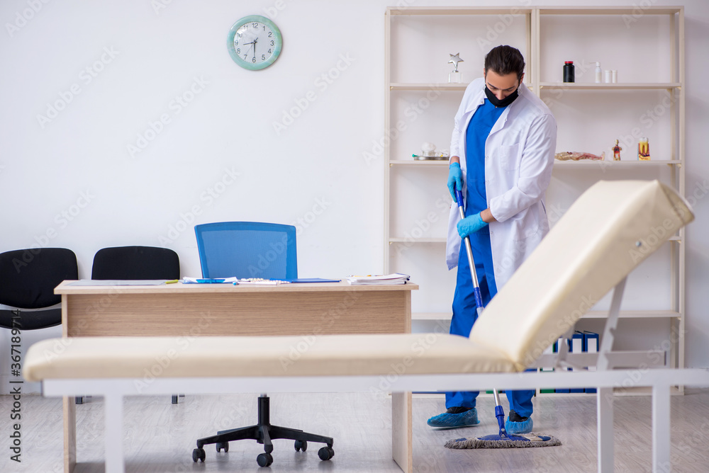 Young male contractor disinfecting clinic in pandemic concept